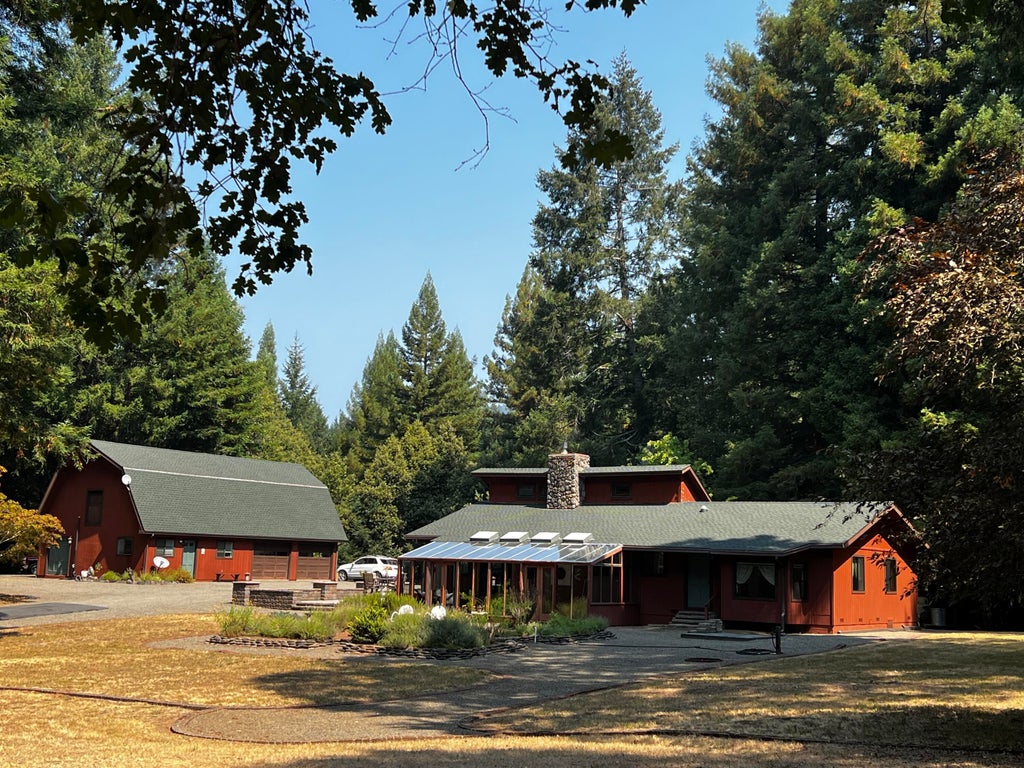 A picturesque photo of a house nestled in a forest, with a large detached garage.